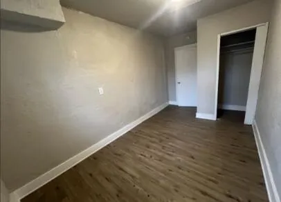 an empty room with wooden floor and closet