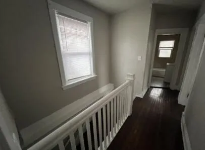 a view of a hallway with wooden floor and stairs