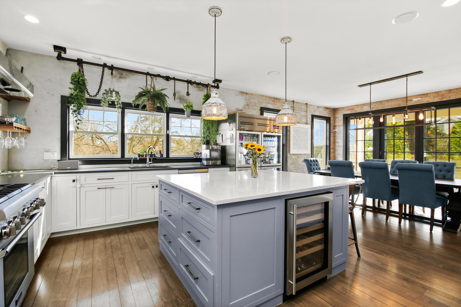 a kitchen with stainless steel appliances granite countertop a sink a stove and chairs with wooden floor
