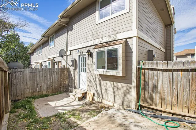 a view of a house with a backyard and wooden fence