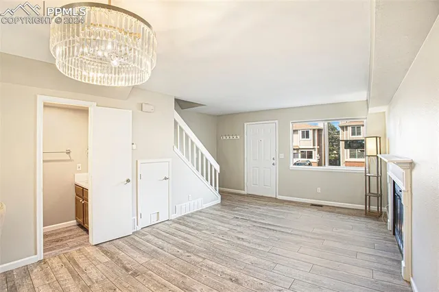 an empty room with wooden floor a ceiling fan and windows