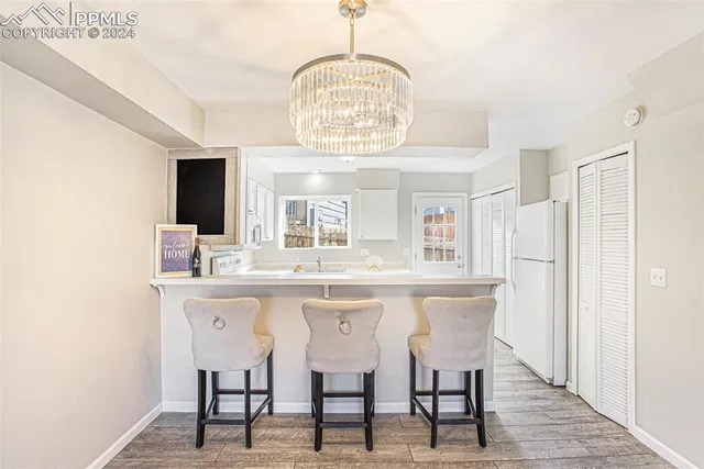 a dining room with wooden floor a chandelier a wooden table and chairs