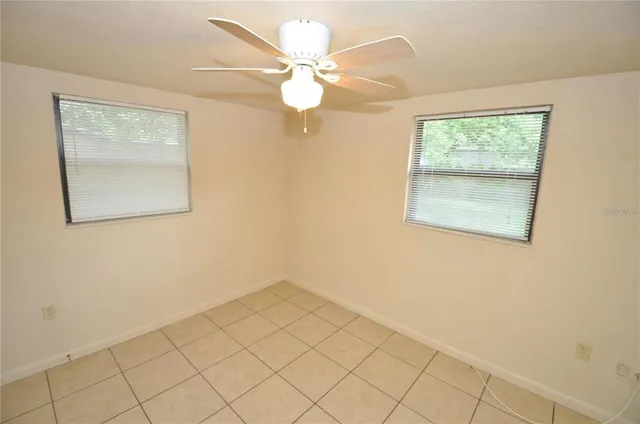 an empty room with windows and fan