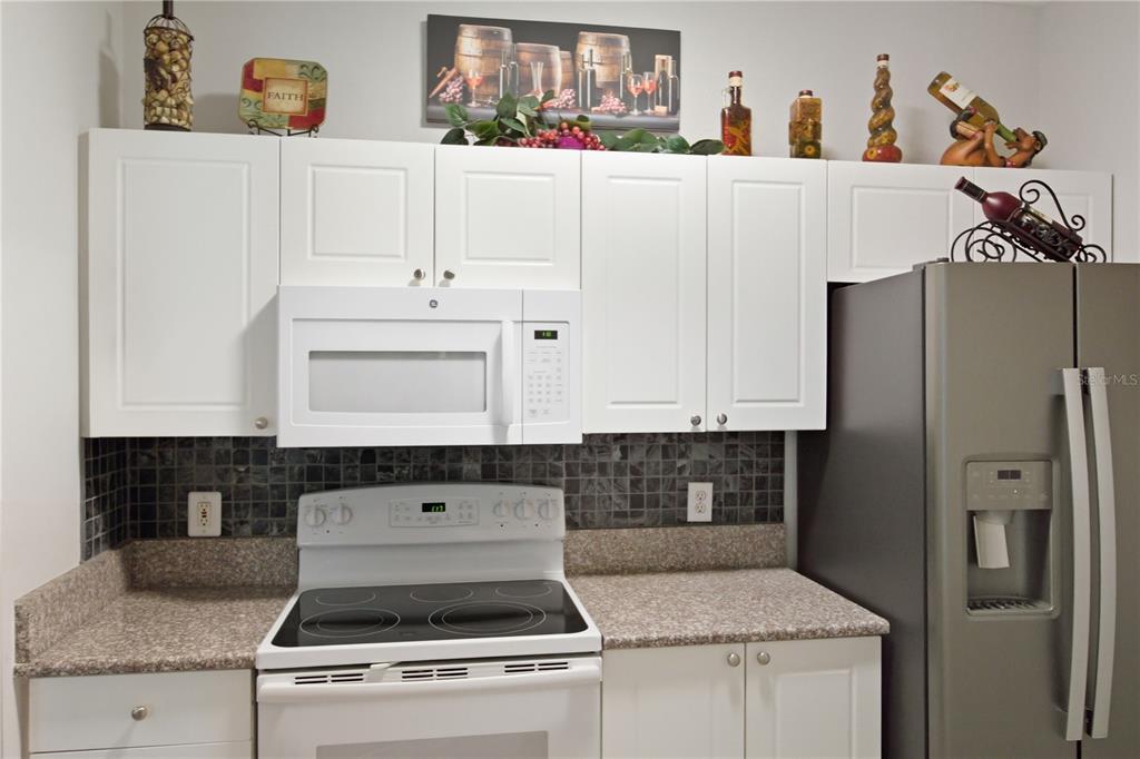 5122 Northridge Road, Unit 107 Sarasota, FL 34238 - Photo 11 of 36 a kitchen with stainless steel appliances granite countertop a stove a refrigerator and a white cabinets