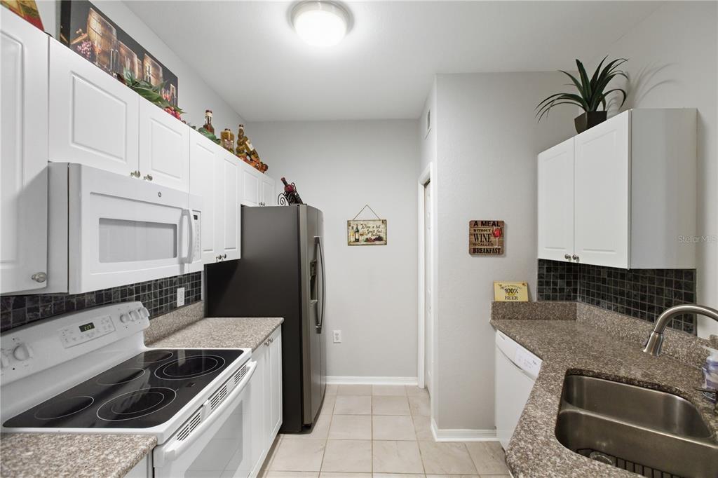 5122 Northridge Road, Unit 107 Sarasota, FL 34238 - Photo 13 of 36 a kitchen with granite countertop a sink stove and refrigerator