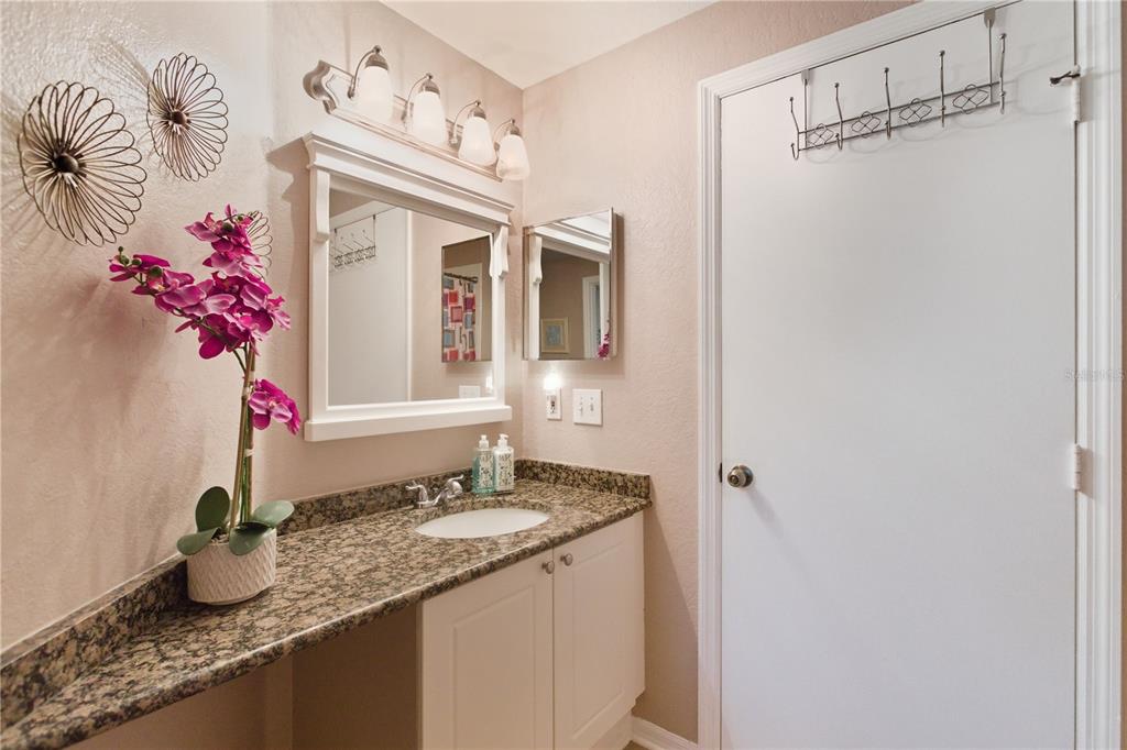 5122 Northridge Road, Unit 107 Sarasota, FL 34238 - Photo 18 of 36 a bathroom with a granite countertop sink a mirror and shower