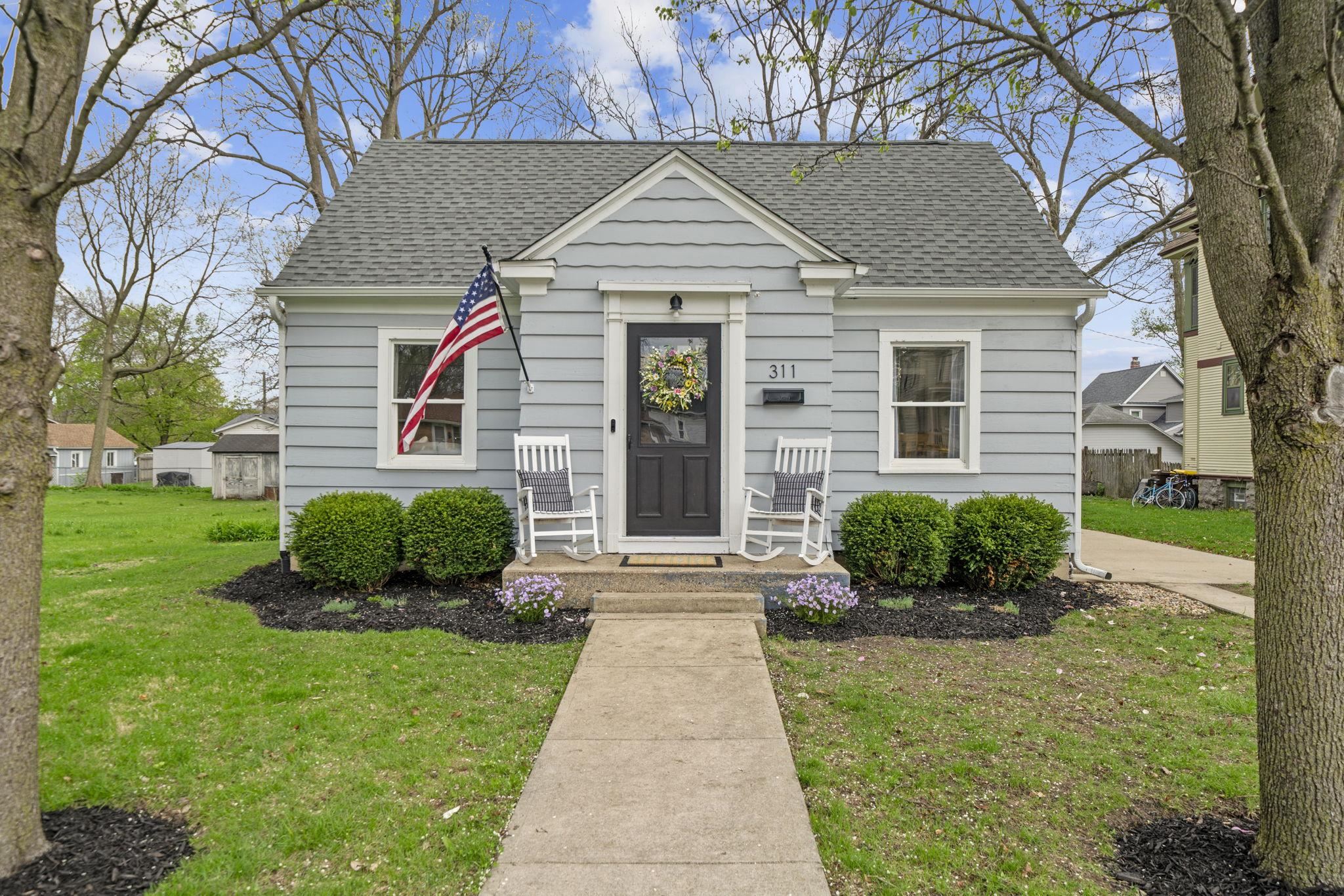 a front view of a house with a yard and potted plants