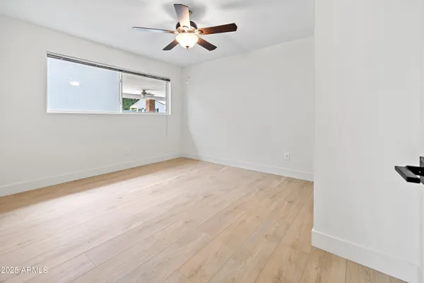 a view of an empty room with window and kitchen view
