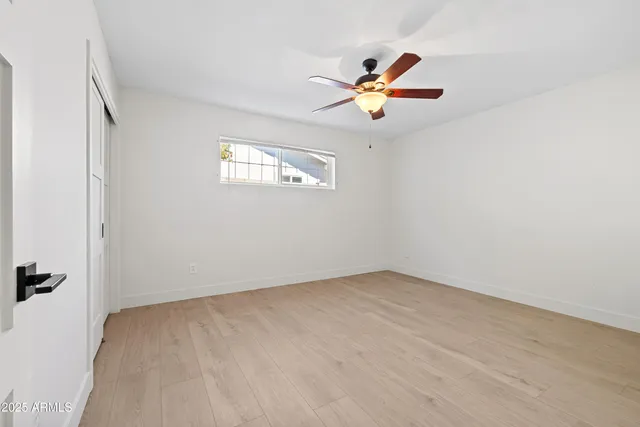 a view of an empty room with furniture and a ceiling fan