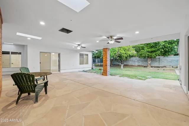 an empty room with chandelier fan and windows