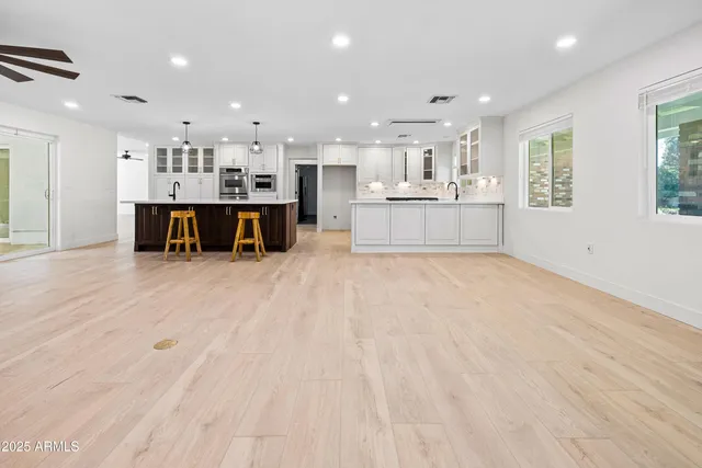a large white kitchen with kitchen island a sink a center island stainless steel appliances and a window