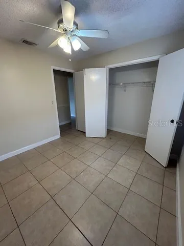 an empty room with a ceiling fan and window