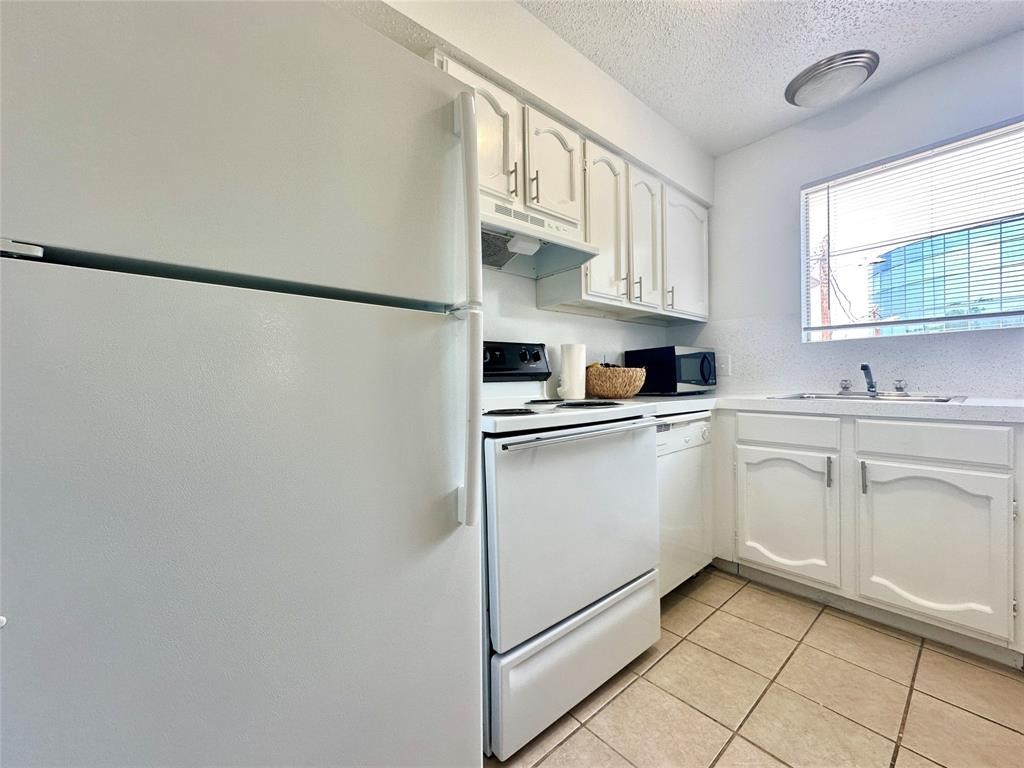 2410 Longview Street, Unit D102 Austin, TX 78705 - Photo 4 of 10 a kitchen with white cabinets and white appliances