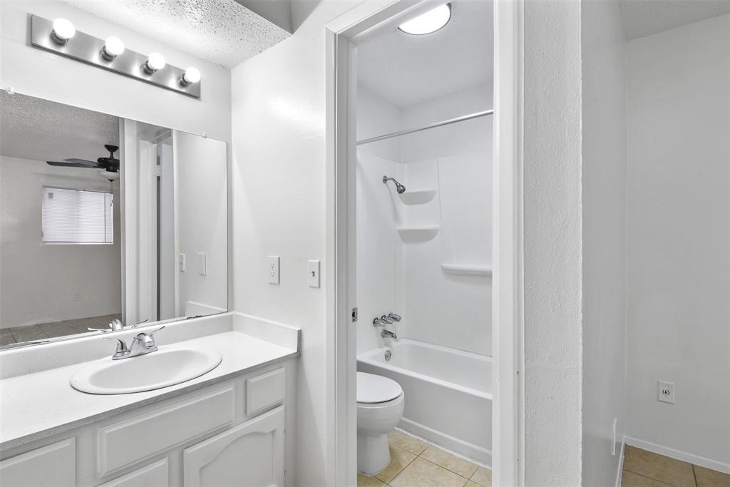 2410 Longview Street, Unit D102 Austin, TX 78705 - Photo 6 of 10 a bathroom with a granite countertop sink toilet a shower and a mirror