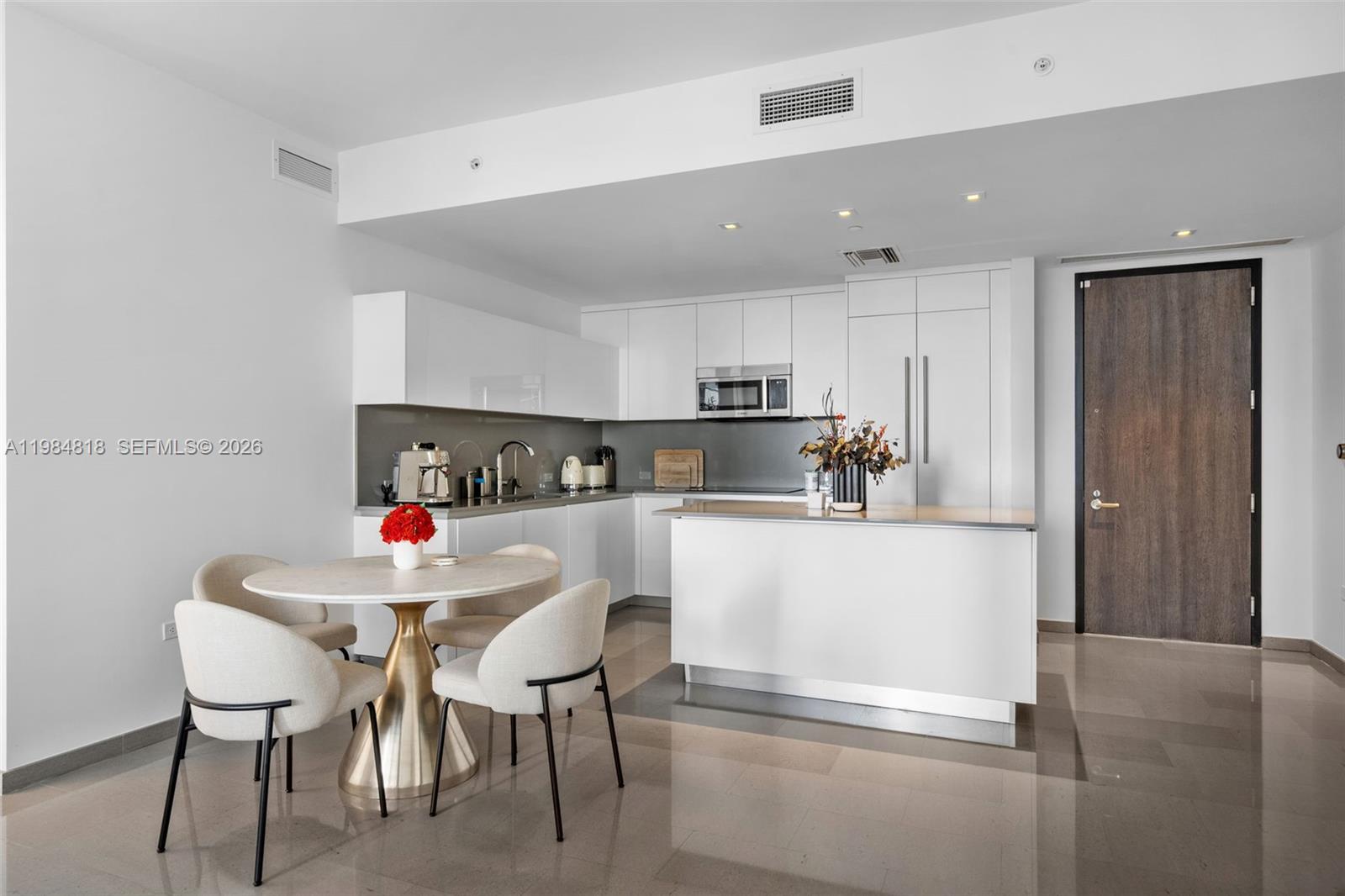 88 Southwest 7th Street, Unit 809 Miami, FL 33130 - Photo 3 of 39 a kitchen with a dining table chairs refrigerator and cabinets