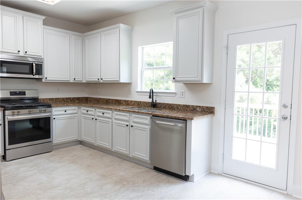 502 Streamside Place Canton, GA 30115 - Photo 9 of 33 a kitchen with granite countertop white cabinets and white appliances