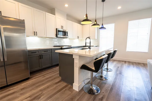 a kitchen with a stove a sink and a flat screen tv