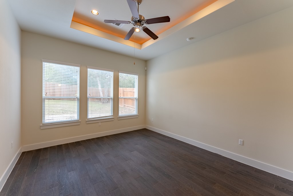 13008 Armaga Springs Road Austin, TX 78727 - Photo 15 of 33 Unfurnished room featuring dark wood finished floors, a ceiling fan, and a raised ceiling