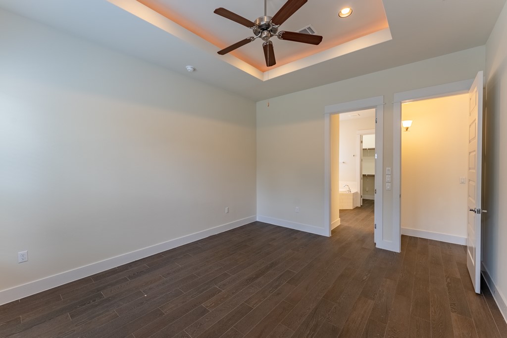 13008 Armaga Springs Road Austin, TX 78727 - Photo 16 of 33 Unfurnished bedroom with a ceiling fan, dark wood-style floors, ensuite bath, a raised ceiling, and recessed lighting