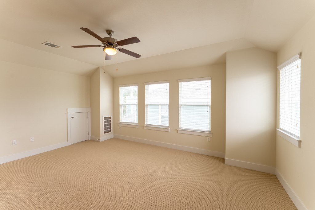 13008 Armaga Springs Road Austin, TX 78727 - Photo 20 of 33 Empty room with light carpet, lofted ceiling, and ceiling fan
