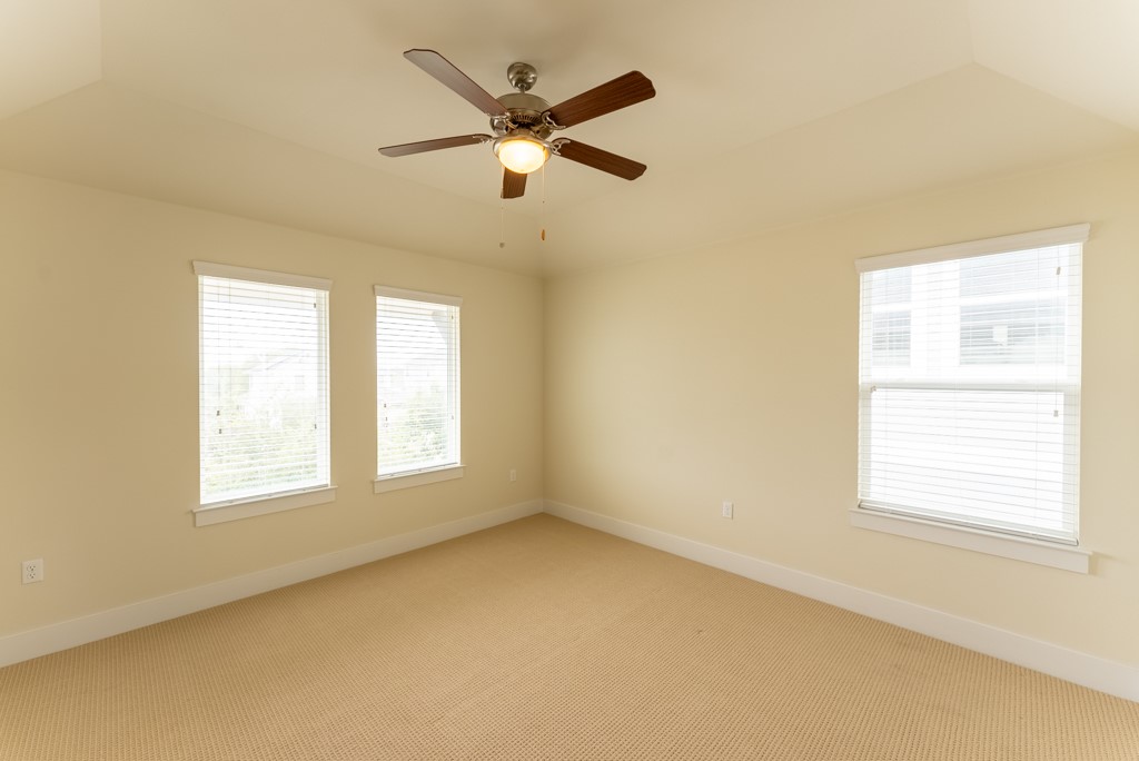 13008 Armaga Springs Road Austin, TX 78727 - Photo 23 of 33 Carpeted spare room with healthy amount of natural light, a ceiling fan, lofted ceiling, and a tray ceiling