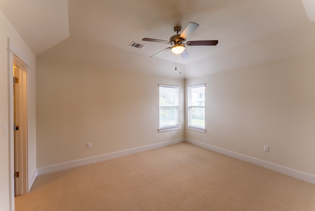 13008 Armaga Springs Road Austin, TX 78727 - Photo 27 of 33 Empty room with vaulted ceiling, light colored carpet, and a ceiling fan