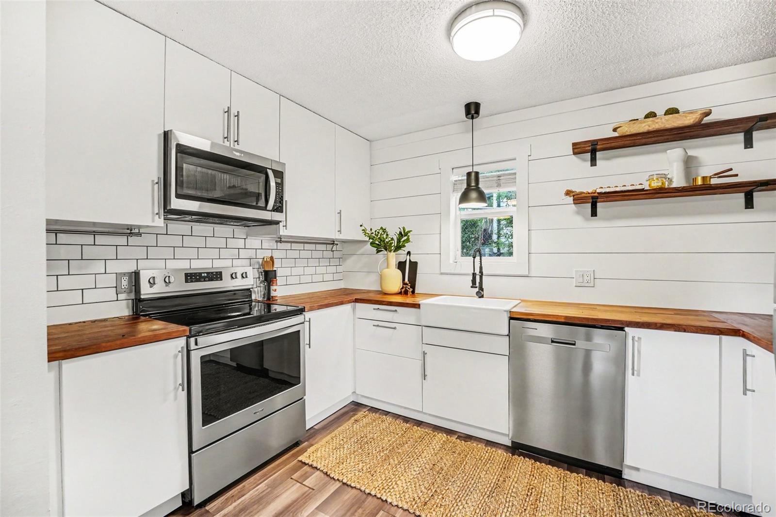 5700 West 28th Avenue, Unit 1 Wheat Ridge, CO 80214 - Photo 6 of 25 a kitchen with stainless steel appliances granite countertop a stove sink and microwave