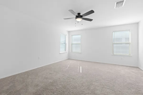 an empty room with windows and fan