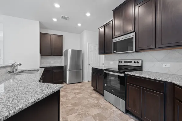 a kitchen with stainless steel appliances granite countertop a sink a stove and a microwave