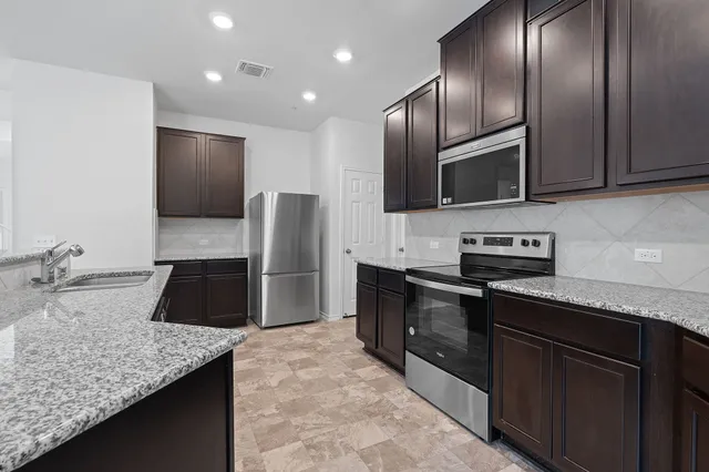 a kitchen with stainless steel appliances granite countertop a sink a stove and a microwave