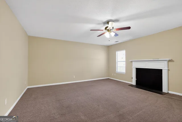 a view of a room with a ceiling fan and a fireplace