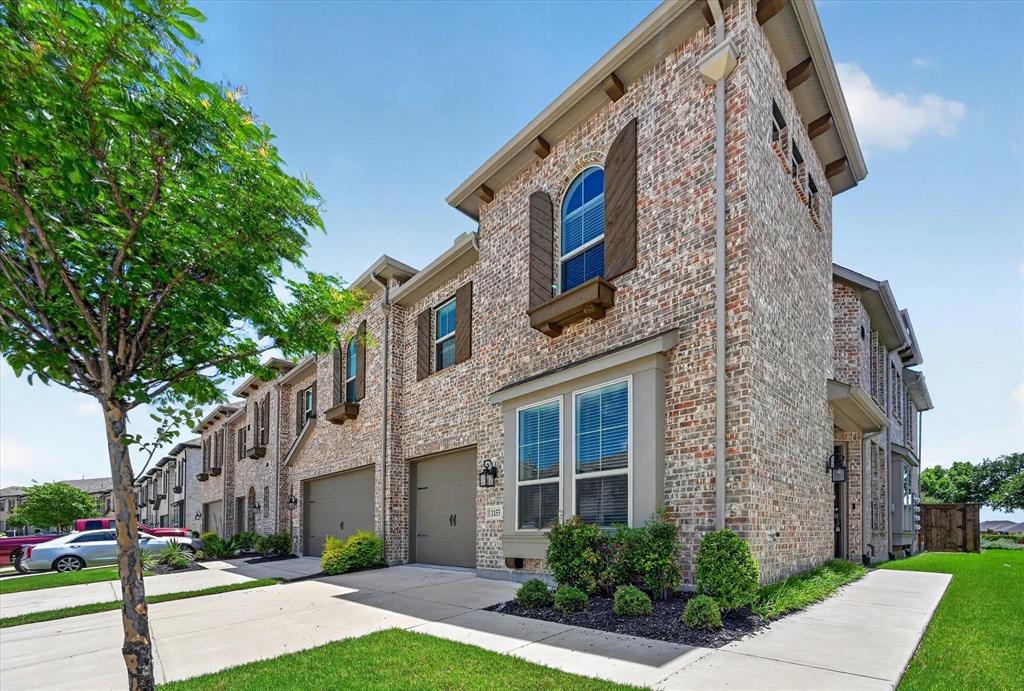 1153 Queensdown Way Forney, TX 75126 - Photo 3 of 26 Brick exterior featuring an arched window with decorative shutters, integrated garage, and a concrete walkway