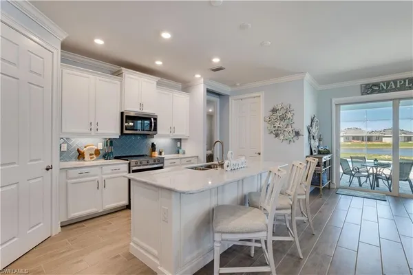 a kitchen with stainless steel appliances granite countertop a stove top oven a sink dishwasher a dining table and chairs with wooden floor