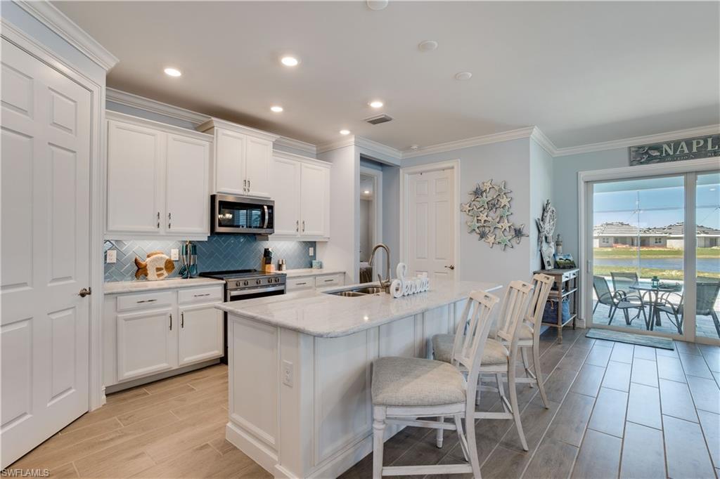 14471 Stillwater Way Naples, FL 34114 - Photo 5 of 20 a kitchen with stainless steel appliances granite countertop a stove top oven a sink dishwasher a dining table and chairs with wooden floor