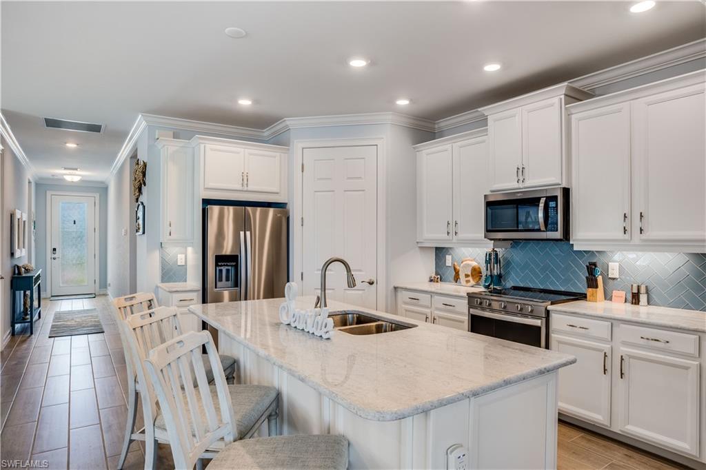 14471 Stillwater Way Naples, FL 34114 - Photo 6 of 20 a kitchen with stainless steel appliances granite countertop a refrigerator a sink dishwasher a stove and white cabinets with wooden floor