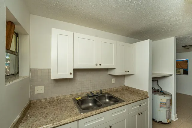 a kitchen with granite countertop a sink a stove and cabinets