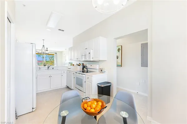 a white kitchen with stainless steel appliances granite countertop a sink and cabinets