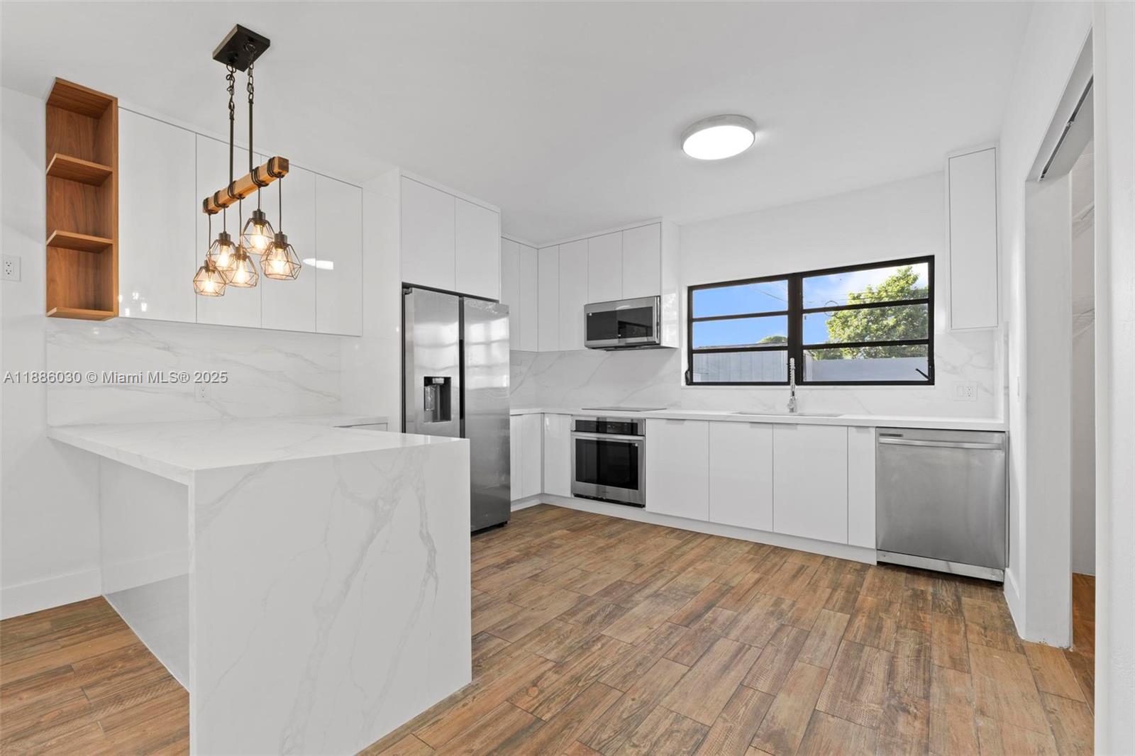 705 East 9th Lane Hialeah, FL 33010 - Photo 11 of 37 a kitchen with stainless steel appliances a white cabinets and a wooden floor