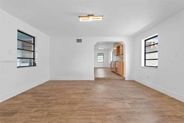 a view of an empty room with window and wooden floor