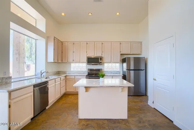 a kitchen with stainless steel appliances granite countertop a refrigerator sink stove and white cabinets