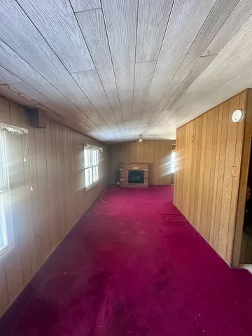 a view of an empty room with kitchen and a window