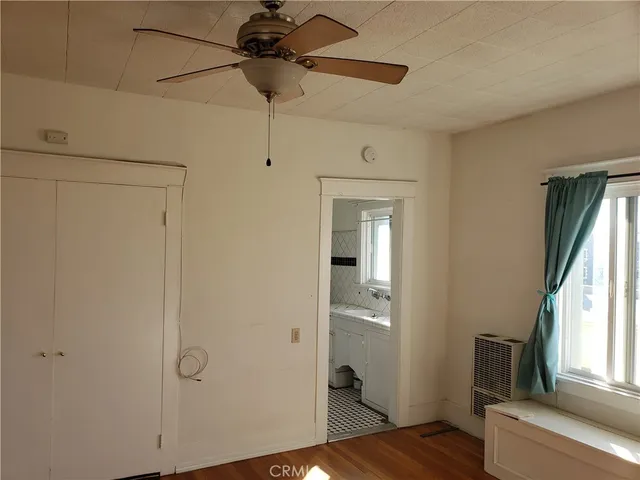 a view of empty room with wooden floor and fan