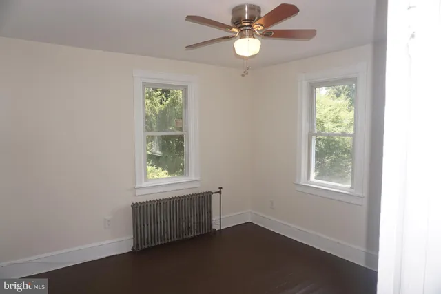 an empty room with windows and fan