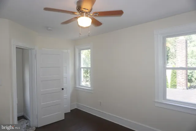 an empty room with windows and fan
