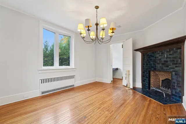 a view of an empty room with wooden floor fireplace and a window