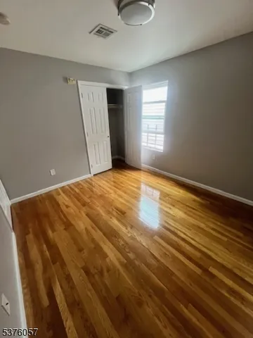 a view of an empty room with window and wooden floor