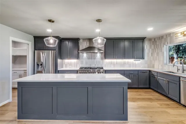 a kitchen with kitchen island a counter space a sink appliances and cabinets