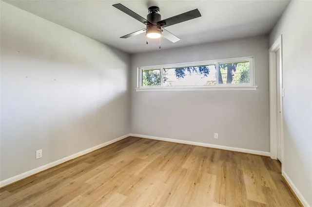 an empty room with a window and a ceiling fan