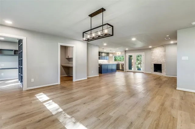 an empty room with wooden floor windows and kitchen view