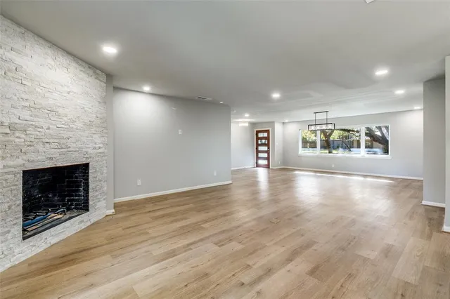 an empty room with wooden floor cabinet and windows